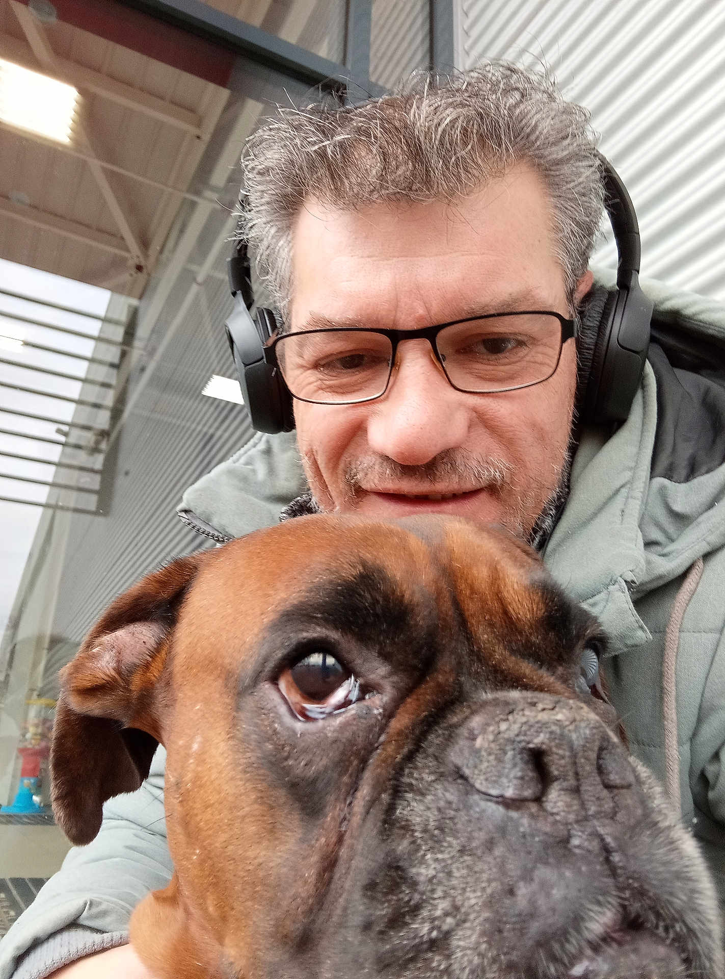 Marley a rejoint le concours — aidez-le/la à gagner de superbes lots ! man, dog, selfie, glasses, headphones, brown_dog, close_up, portrait, indoor, smile, facial_hair, casual_clothing, canine, pet, companion, headshot, friendly, indoor_lighting, human, animal