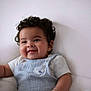 Caleb joined the competition — help win amazing prizes! baby, child, smiling, curly_hair, blue_overall, white_shirt, sitting, cute, happy, infant, portrait, soft_background, indoors, one_person, close_up, chubby_cheeks, light_skin, baby_clothing, playful, adorable