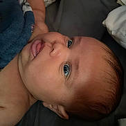 Violet is registered to the contest to win money with this photo: baby, infant, newborn, face, eyes, tongue, skin, hair, blanket, bedding, close_up, portrait, lying_down, cheek, nose, ear, expression, curious, cute, indoor