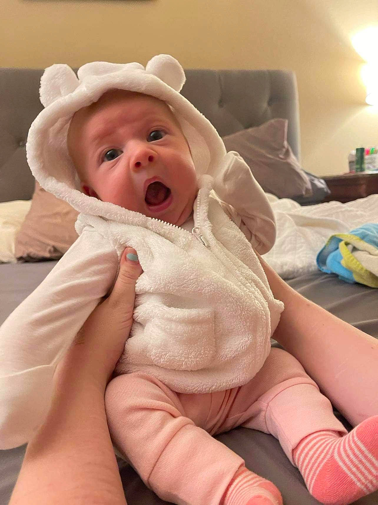 Constance is registered to the contest to win money with this photo: abdomen, baby, baby_toddler_clothing, cheek, child, comfort, eye, eyebrow, foot, iris, knee, linens, lip, mouth, nose, person, sitting, skin, thigh, thumb