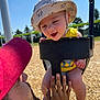 adult_hand, baby, beard, blue_sky, child, dinosaur_print, fun, happy, hat, outdoor, person, playground, red_cap, seat, smiling, sunny, swing, trees, woodchips, yellow_shirt