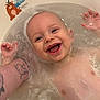 baby, bath, water, smile, happy, child, tattoo, arm, bathtub, skin, face, joy, cute, floating, infant, playful, expression, support, sticker, relaxation