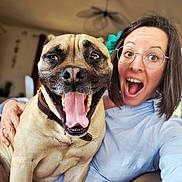 Doug participe au concours pour gagner de l'argent avec cette photo : woman, dog, glasses, smile, tongue_out, indoor, happy, face, pet, collar, flower, hair, casual_clothing, furniture, hand, brown_dog, short_hair, portrait, excited, selfie