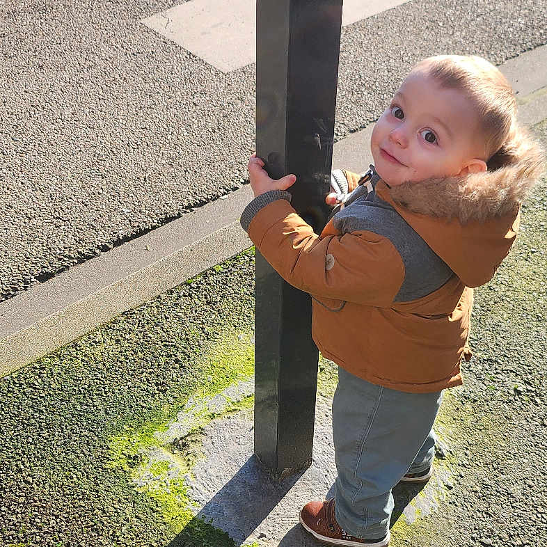 Aménadiel a rejoint le concours — aidez-le/la à gagner de superbes lots ! child, coat, crosswalk, hood, jacket, looking_up, manhole, moss, outdoors, pavement, playful, pole, portrait, shadow, shoe, sidewalk, standing, street, sunlight, toddler