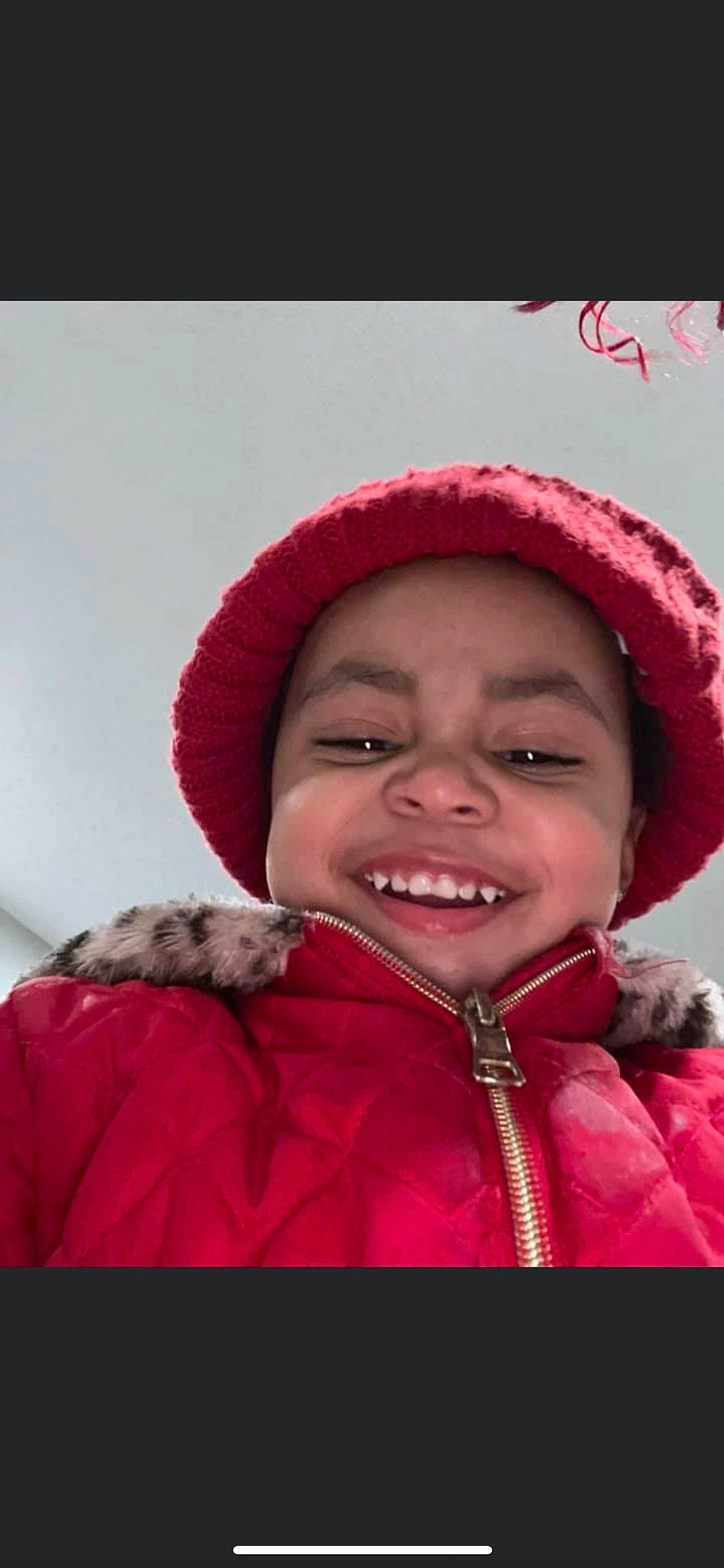 Ezra is registered to the contest to win money with this photo: cap, cheek, chin, clothing, eye, eyebrow, facial_expression, flash_photography, happy, headwear, human, jacket, joy, lip, nose, outerwear, parka, person, pink, red