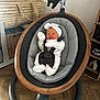 newborn, baby, sleeping, baby_rocker, headband, white_clothing, indoor, wooden_floor, basket, woven_basket, modern_furniture, baby_seat, infant, cozy, relaxed, child, soft_lighting, home, cute, peaceful