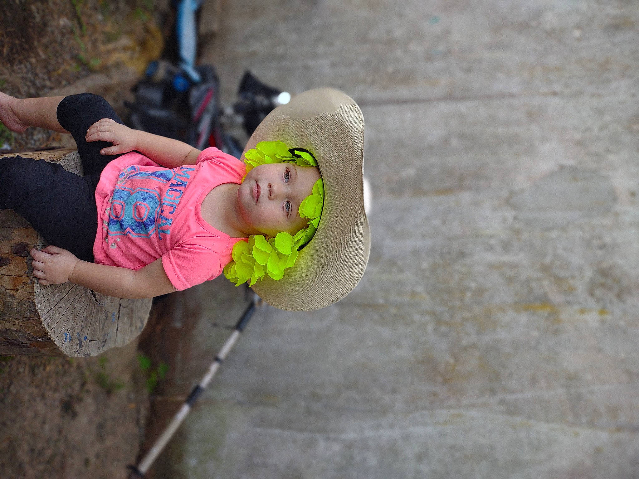 Lillian joined the competition — help win amazing prizes! adventure, baby, cap, competition_event, fun, grass, happy, hat, headwear, human_leg, leisure, person, personal_protective_equipment, play, recreation, sandal, shorts, sidewalk, sitting, t_shirt