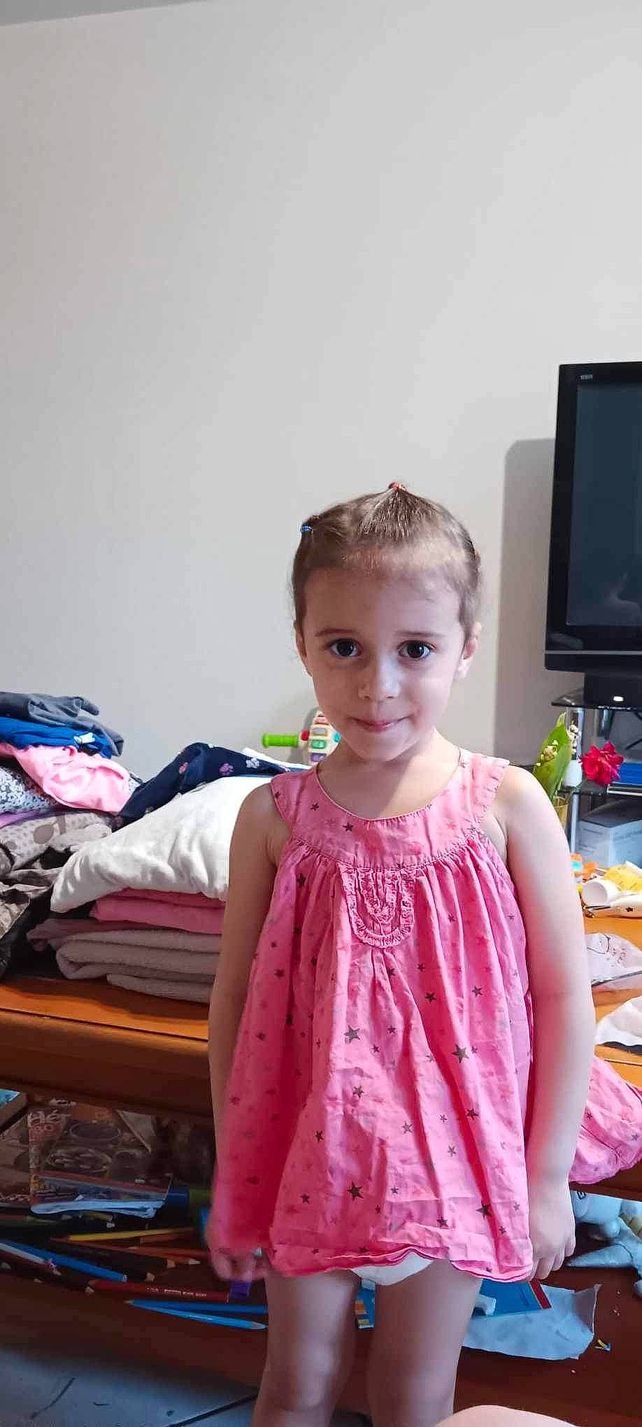 Leïla participe au concours pour gagner de l'argent avec cette photo : baby_toddler_clothing, child, computer_monitor, day_dress, event, fashion_design, fun, hair, happy, home_appliance, joy, led_backlit_lcd_display, magenta, pattern, peach, person, room, sitting, sleeve, standing