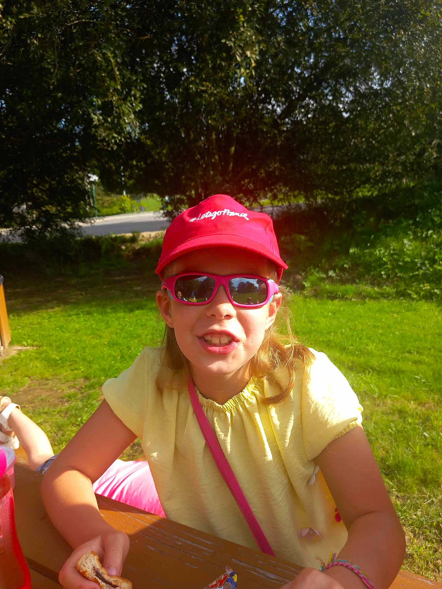 Louanne a rejoint le concours — aidez-le/la à gagner de superbes lots ! baseball_cap, cap, event, eyewear, fun, glasses, goggles, grass, happy, headwear, leisure, magenta, people_in_nature, person, personal_protective_equipment, pink, plant, recreation, sitting, summer