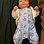 baby, infant, onesie, cartoon_pattern, socks, blanket, teddy_bear, lying_down, curious_expression, indoor, child, cute, soft_toy, colorful_clothing, small_hands, head, face, blue_onesie, pink_socks, playful