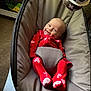 baby, infant, red_clothing, heart_pattern, baby_seat, smiling, happy, indoor, toy, cushion, face, person, cute, comfort, sleepwear, footwear, carpet, zipper, head, expression