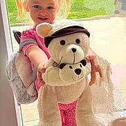 Inaya participe au concours pour gagner de l'argent avec cette photo : child, girl, blonde_hair, pigtails, teddy_bear, stuffed_animal, indoor, glass_door, backpack, pink_shirt, red_shorts, smiling, happy, toy, plush, person, standing, home, daylight, floor