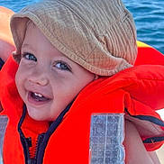 Milan participe au concours pour gagner de l'argent avec cette photo : toddler, child, smile, hat, bucket_hat, life_jacket, orange, water, ocean, outdoor, happy, baby, face, person, summer, sunlight, vacation, safety, cute, closeup