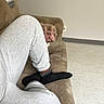 brown, casual, comfort, couch, cozy, curious, dog, floor, furniture, gray, home, indoor, living_room, peeking, person, pet, relaxing, socks, sweatpants, wall