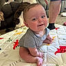 baby, infant, smiling, play_mat, dog, couch, person, legs, home, indoor, cute, child, happy, sitting, shorts, carpet, animal, pet, human, casual
