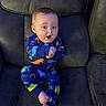Nicholas joined the competition — help win amazing prizes! baby, child, dinosaur_onesie, clapping, happy, cute, sitting, couch, blue_clothing, indoor, infant, smile, barefoot, person, young_child, furniture, home, expression, playful, colorful