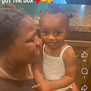 Promises Johnson is registered to the contest to win money with this photo: toddler, woman, child, indoor, kitchen, smiling, holding, text_overlay, love, affection, family, person, countertop, door, cabinet, hairstyle, white_clothing, emojis, portrait, happy