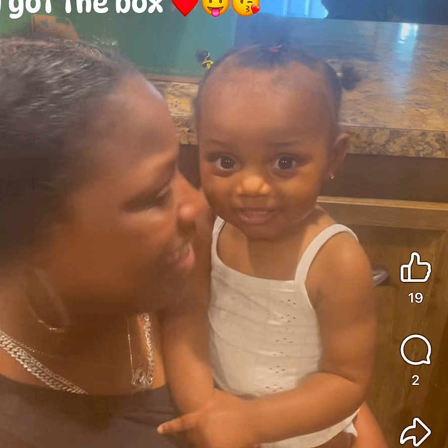 Promises Johnson is registered to the contest to win money with this photo: toddler, woman, child, indoor, kitchen, smiling, holding, text_overlay, love, affection, family, person, countertop, door, cabinet, hairstyle, white_clothing, emojis, portrait, happy