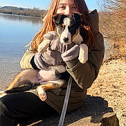 Moka a rejoint le concours — aidez-le/la à gagner de superbes lots ! puppy, person, gloves, jacket, lake, water, tree_stump, outdoor, sunlight, dog, animal, nature, fall, leash, sitting, brown_hair, calm, sky, bare_trees, young_person