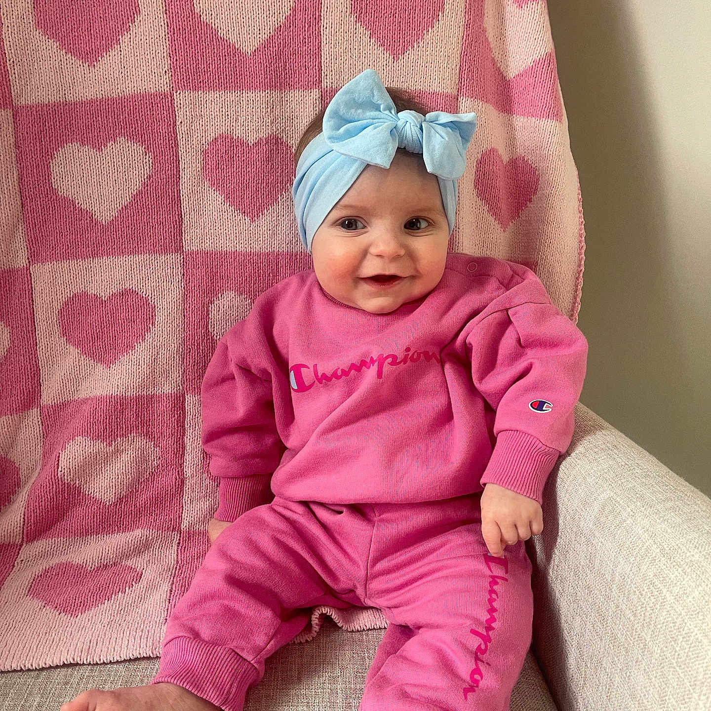 Whitley joined the competition — help win amazing prizes! baby, blanket, clothing, couch, cushion, face, furniture, happy, hat, head, homedecor, pajamas, pants, person, photography, portrait, purple, quilt, sitting, smile