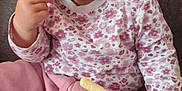 Klaudia joined the competition — help win amazing prizes! baby, blanket, cartoon, child, clothing, couch, cute, face, floral_shirt, food, hand, happy, indoor, infant, munching, pink_pants, playful, sitting, snack, snack_food
