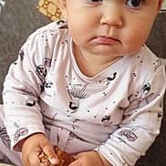 Klaudia is registered to the contest to win money with this photo: baby, child, pajamas, food, plate, hands, face, eyes, expression, pout, sitting, indoors, cozy, curious, skin, head, young, person, snack, clothing