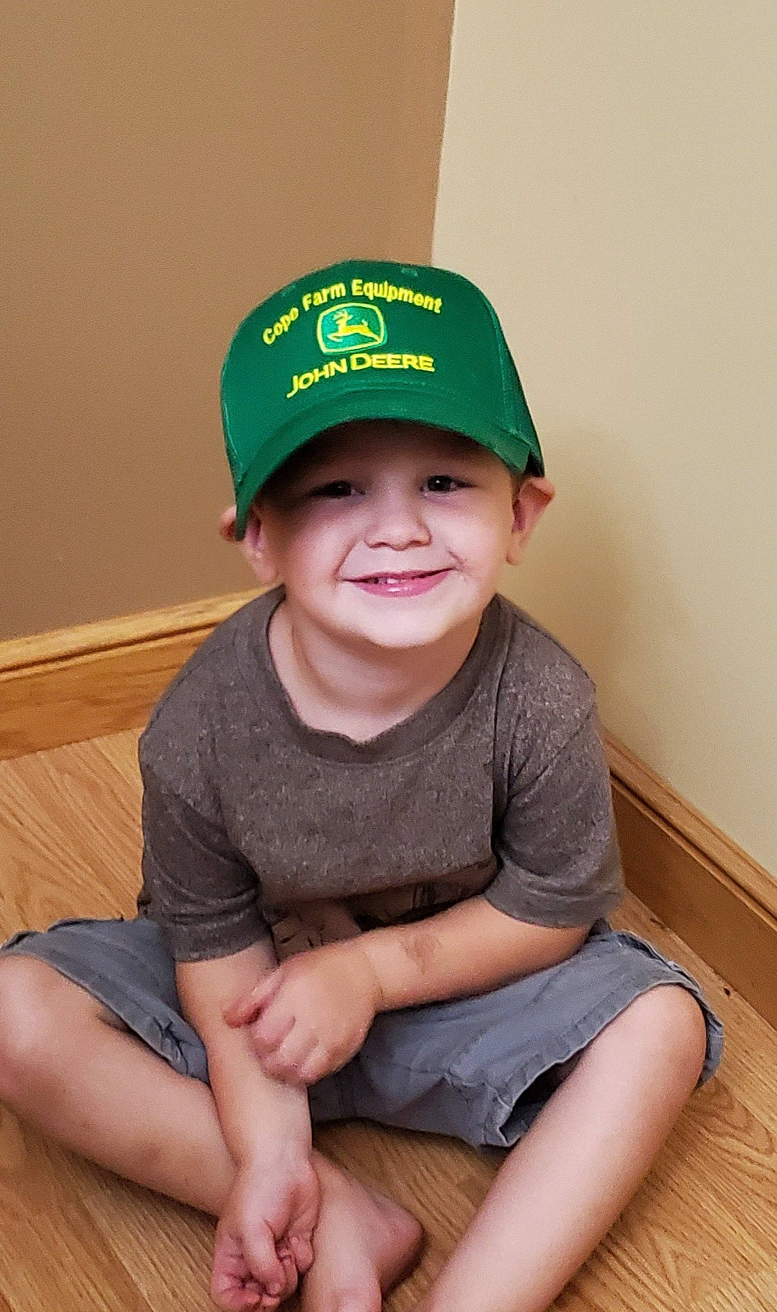 Lucas is registered to the contest to win money with this photo: baseball_cap, cap, child, fashion_accessory, green, hat, headgear, headwear, joy, person, sitting, smile, t_shirt, toddler