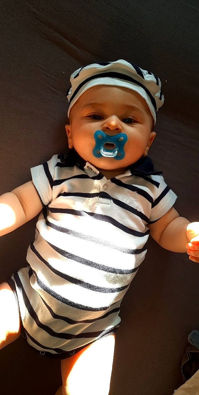 Louka participe au concours pour gagner de l'argent avec cette photo : baby, baby_toddler_clothing, cap, cheek, child, elbow, event, eye, eyelash, finger, fun, gesture, happy, headwear, nose, person, sitting, sleeve, smile, t_shirt