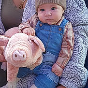 Justin is registered to the contest to win money with this photo: baby, child, plush_toy, pig, denim_overalls, knit_hat, bear_design, cozy_clothing, blanket, person, jewelry, necklace, hand, soft_texture, indoor, portrait, cute, infant, warm, comfort