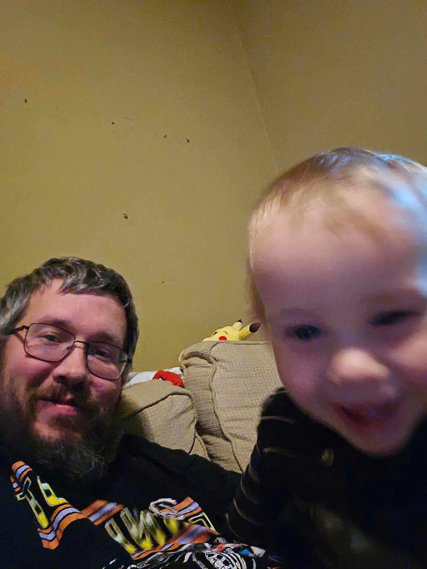 Xander joined the competition — help win amazing prizes! man, child, toddler, beard, glasses, couch, indoor, plush_toy, pikachu, smile, motion_blur, casual, striped_clothing, living_room, happy, portrait, person, furniture, relaxed, home