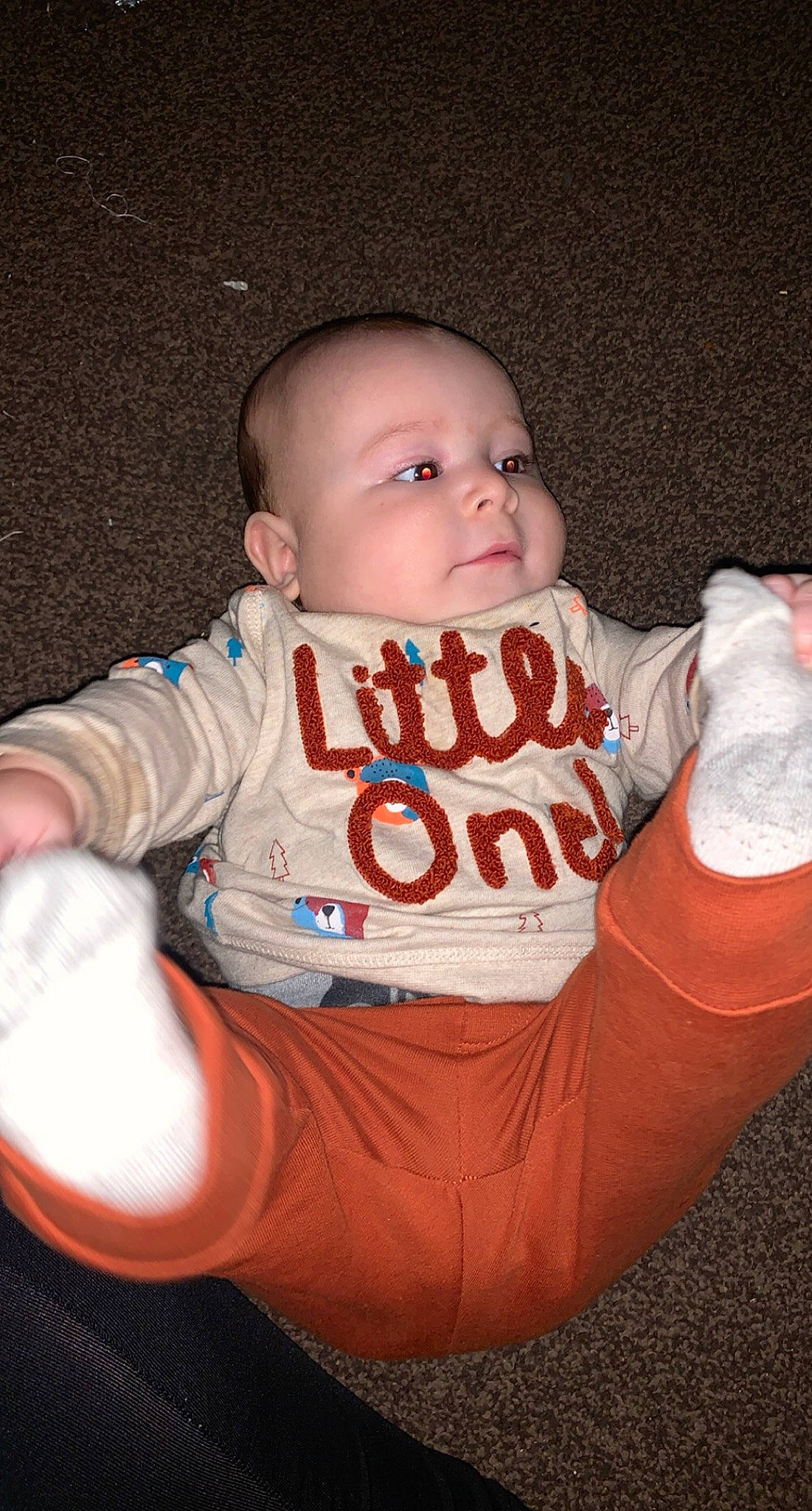 Teddy is registered to the contest to win money with this photo: arm, baby, baby_toddler_clothing, cheek, comfort, finger, flash_photography, fun, gesture, happy, human_body, mouth, nose, orange, outerwear, person, skin, sleeve, t_shirt, thumb