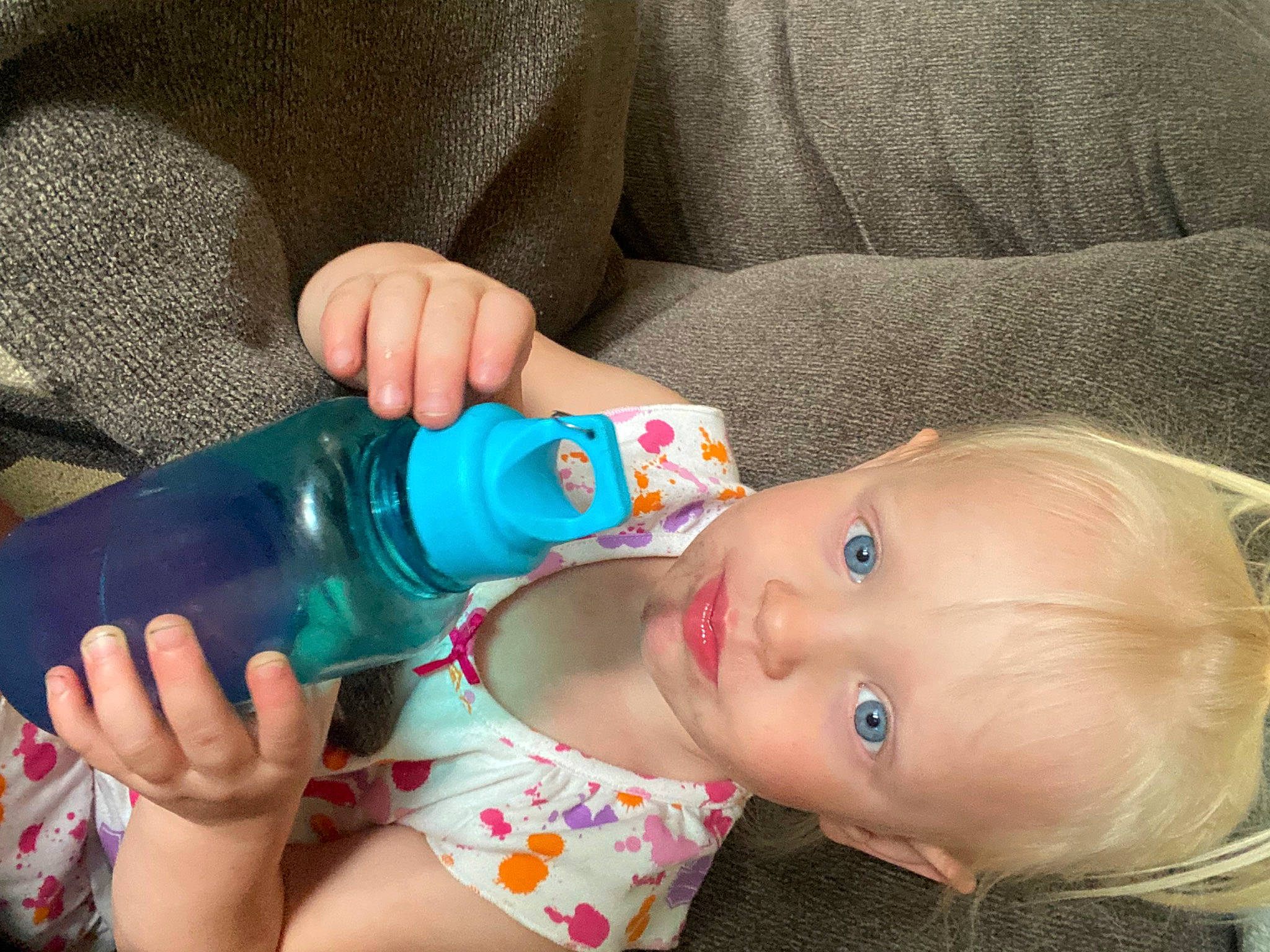 Raelyn is registered to the contest to win money with this photo: baby_products, cheek, child, drink, drinking, drinkware, ear, electric_blue, eyelash, finger, fluid, hand, mouth, nail, nose, person, plastic_bottle, skin, toddler, water