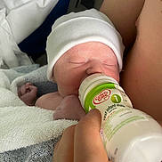 Albie joined the competition — help win amazing prizes! newborn, baby, infant, bottle, feeding, milk, hand, white_hat, towel, sleeping, closeup, skin, person, human, bed, rest, nurture, care, parent, comfort