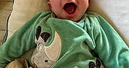 Elyo a rejoint le concours — aidez-le/la à gagner de superbes lots ! adorable, baby, blanket, bouncer, cheeks, cushion, cute, eyes, face, green_clothing, happy, indoor, infant, laughing, mouth_open, onesie, portrait, rhino_applique, smile, soft_texture