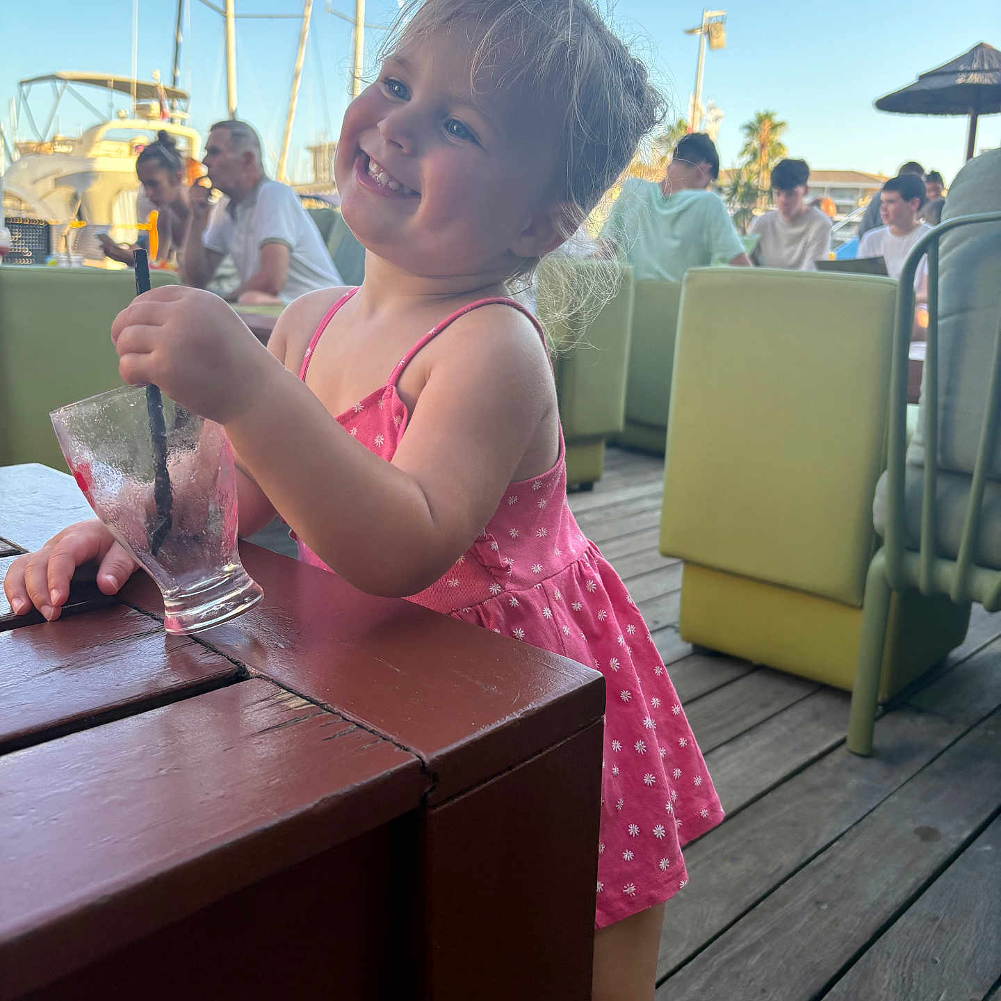 Eulalie participe au concours pour gagner de l'argent avec cette photo : boat, casual, child, daytime, girl, glass, happy, marina, outdoor, people, person, pink_dress, relaxed, smiling, straw, summer, sunlight, table, vacation, wooden_floor