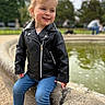 Eulalie a rejoint le concours — aidez-le/la à gagner de superbes lots ! casual_clothing, child, daylight, fountain, grass, happy, jeans, leather_jacket, outdoor, park, person, playful, portrait, sitting, smile, sneakers, stone, toddler, trees, young_child