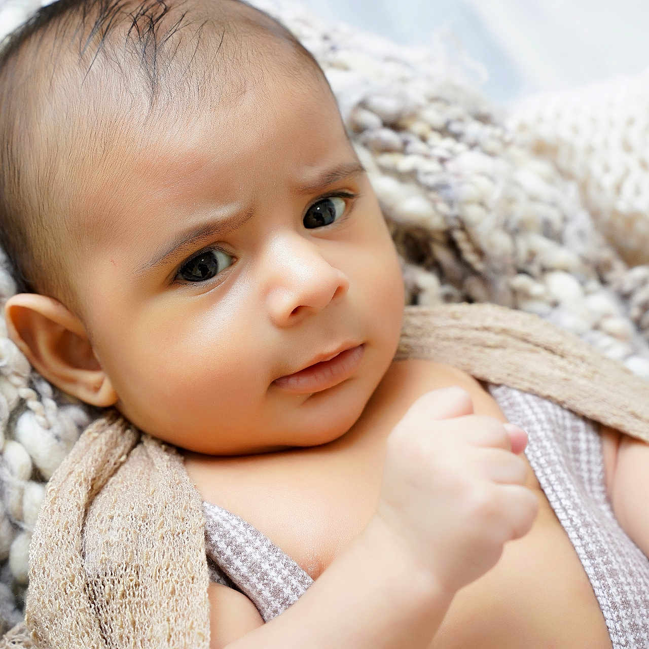 Matias is registered to the contest to win money with this photo: baby, bedding, blanket, close_up, cozy, curious, ear, expression, eyelashes, eyes, face, hand, indoors, infant, knit_blanket, newborn, portrait, skin, soft_texture, wrapped
