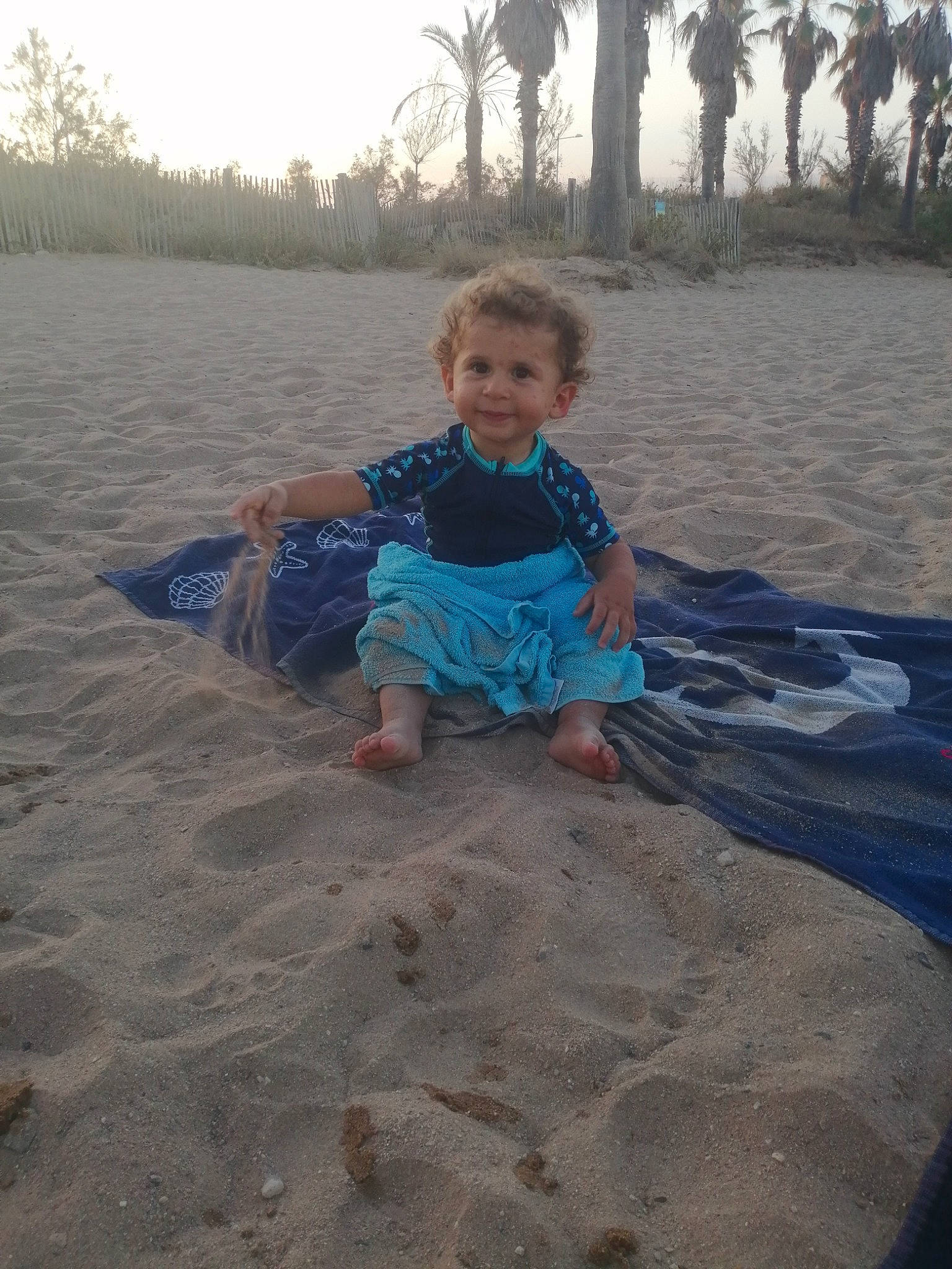 Thiago a rejoint le concours — aidez-le/la à gagner de superbes lots ! baby, baby_toddler_clothing, beach, child, fun, grass, hat, horizon, joy, landscape, morning, palm_tree, person, plant, sand, sitting, sky, smile, t_shirt, toddler