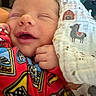 Lennox is registered to the contest to win money with this photo: newborn, baby, infant, sleeping, face, portrait, smiling, closed_eyes, mouth, hand, blanket, swaddle, colorful_clothing, red_outfit, patterned_fabric, farm_animals, indoor, closeup, cozy, resting