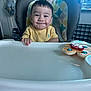 Amir is registered to the contest to win money with this photo: baby, high_chair, smile, yellow_shirt, toy, kitchen, child, face, expression, indoor, seat, feeding, person, hair, furniture, cute, happy, table, playful, infant