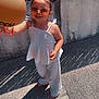 accessory, balloon, casual, child, clothing, concrete, fashion, fence, girl, hair_buns, happy, outdoor, pavement, person, playful, shadow, smiling, summer, sunglasses, sunlight