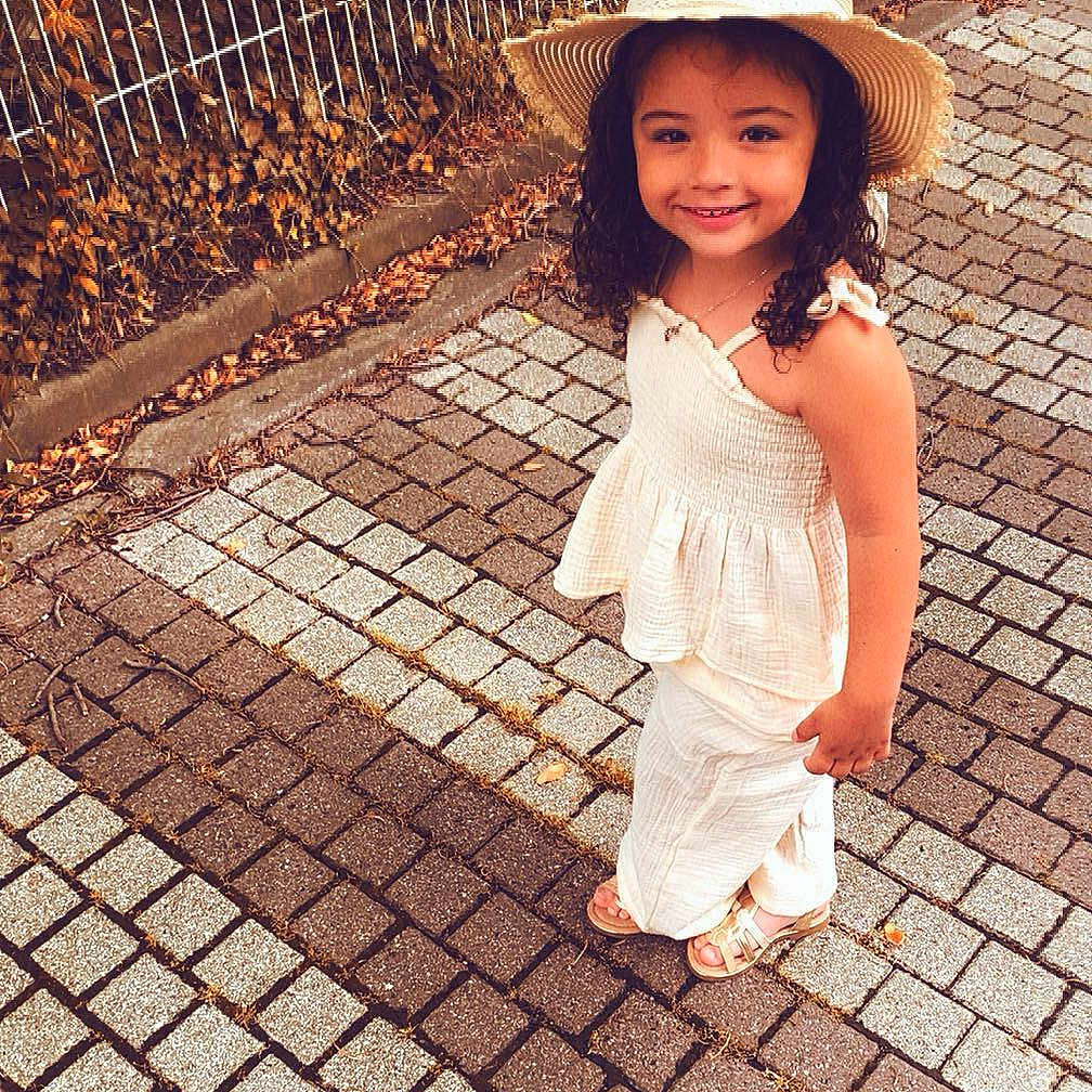 Ruby participe au concours pour gagner de l'argent avec cette photo : autumn_leaves, brick, casual, child, curly_hair, cute, daylight, fence, girl, happy, hat, nature, outdoor, pavement, portrait, sandals, smile, standing, summer_clothing, young