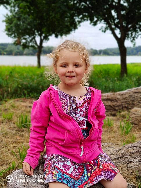 Lilly participe au concours pour gagner de l'argent avec cette photo : child, child_model, clothing, dress, grass, jacket, joy, magenta, outerwear, pattern, person, photography, pink, plant, shorts, sitting, smile, spring, summer, textile