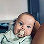 baby, blue_eyes, child, close_up, comfort, curious, cute, face, human, indoors, infant, light_green, pacifier, portrait, ribbed_clothing, sitting, skin, soft_focus, warm, young_child