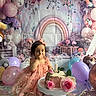 child, baby, birthday, cake, balloons, pink_dress, flower, decoration, party, smile, toddler, celebration, candle, table, present, happy, cute, indoors, portrait, colorful