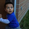 blue_shirt, brick_wall, casual_clothing, child, curious, daylight, doorway, expression, flooring, grass, looking_back, motion, outdoor, person, playful, short_hair, side_view, small_hand, toddler, young_child