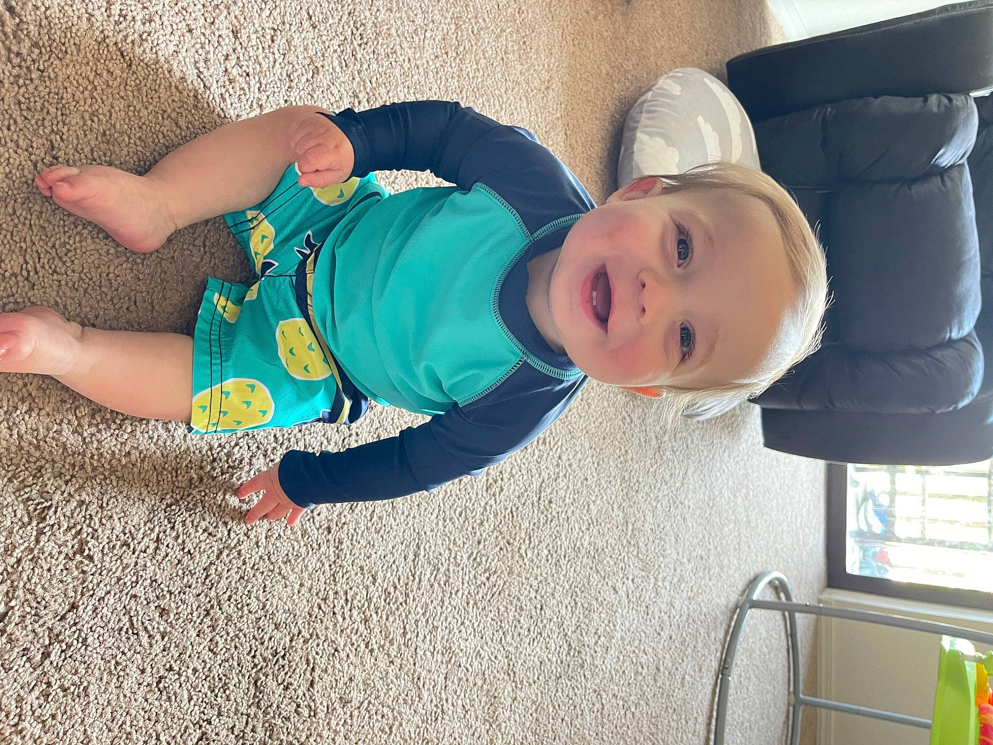 Ezra is registered to the contest to win money with this photo: baby, baby_laughing, baby_products, baby_toddler_clothing, child, comfort, electric_blue, eye, flooring, fun, hat, human_leg, joy, leg, person, sitting, sleeve, smile, sock, t_shirt