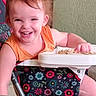 toddler, child, smiling, high_chair, snack, orange_shirt, indoor, baby, face, hand, feeding, seat, colorful, pattern, happy, person, furniture, playful, cute, young