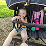 Penelope joined the competition — help win amazing prizes! toddler, stroller, child, outdoor, smiling, grass, sunny, bottle, footwear, sandals, playful, seatbelt, double_stroller, pink, black, daylight, hands, legs, person, happy