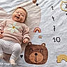 Alyzée a rejoint le concours — aidez-le/la à gagner de superbes lots ! baby, infant, smiling, lying_down, blanket, bear, rainbow, numbers, clothing, sweater, leggings, hair_clip, happy, cute, child, soft_texture, floor, indoors, portrait, cozy